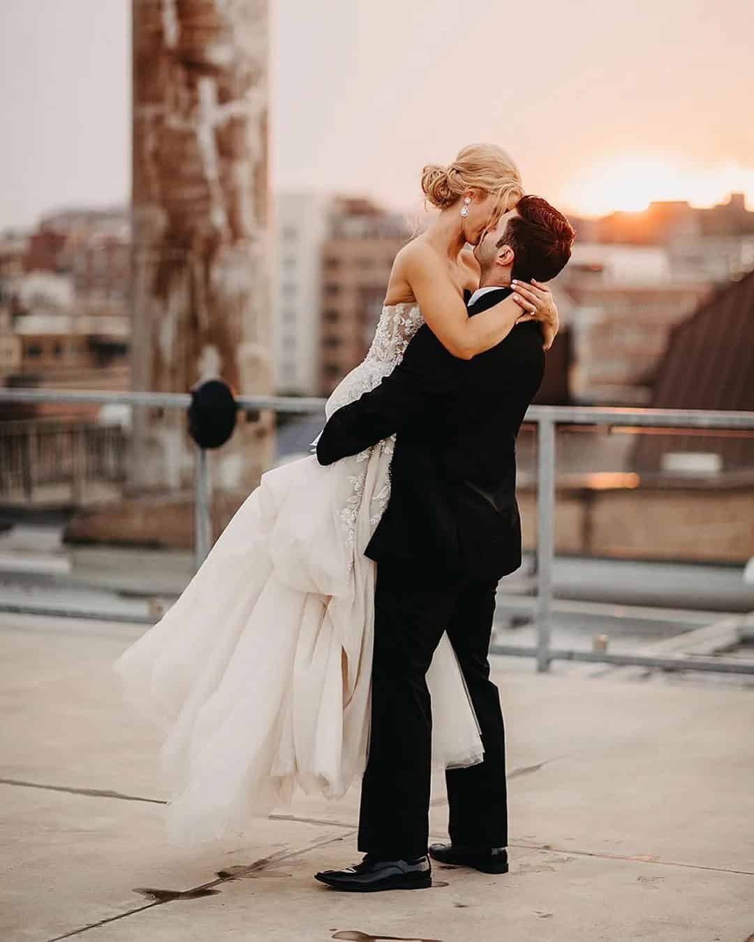 Groom Holds Bride In His Arms And Kisses