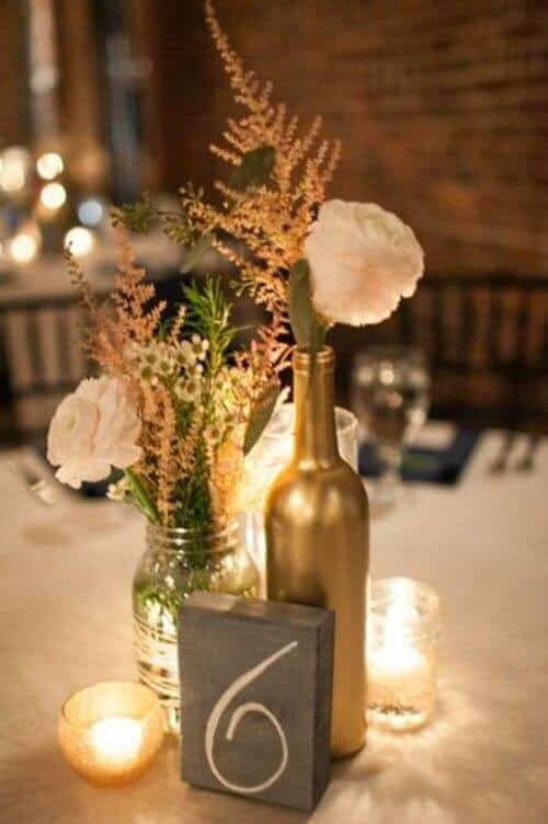 Gold-painted wine bottle centerpieces with wildflowers