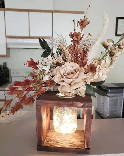 Lit-up mason jars with autumn-colored flowers