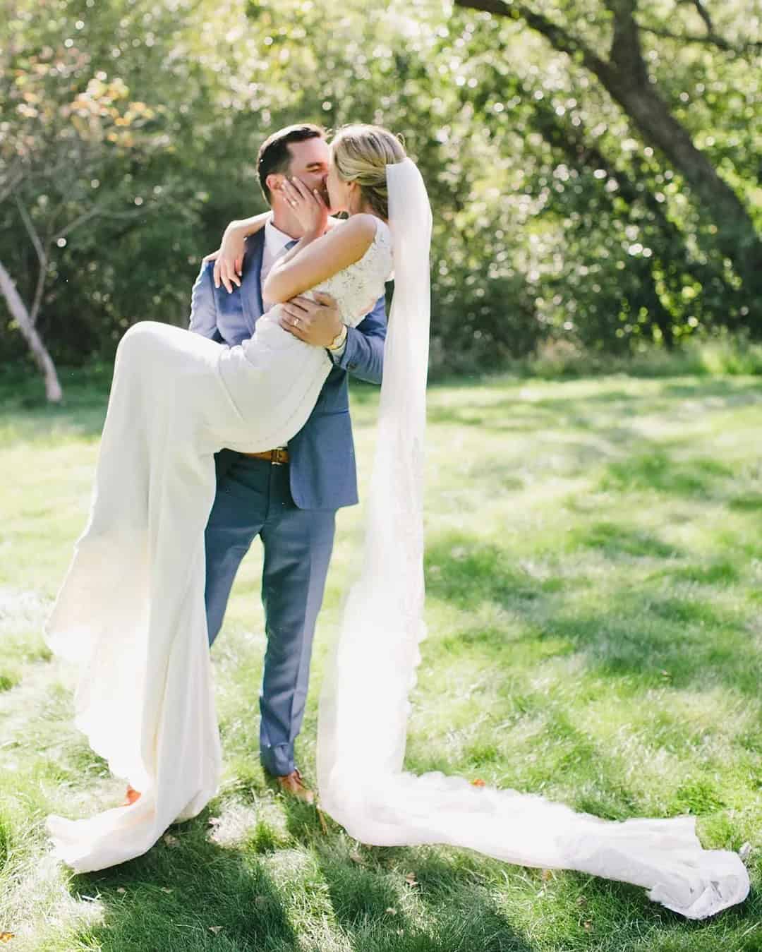 Groom Holds Bride In His Arms And Kisses