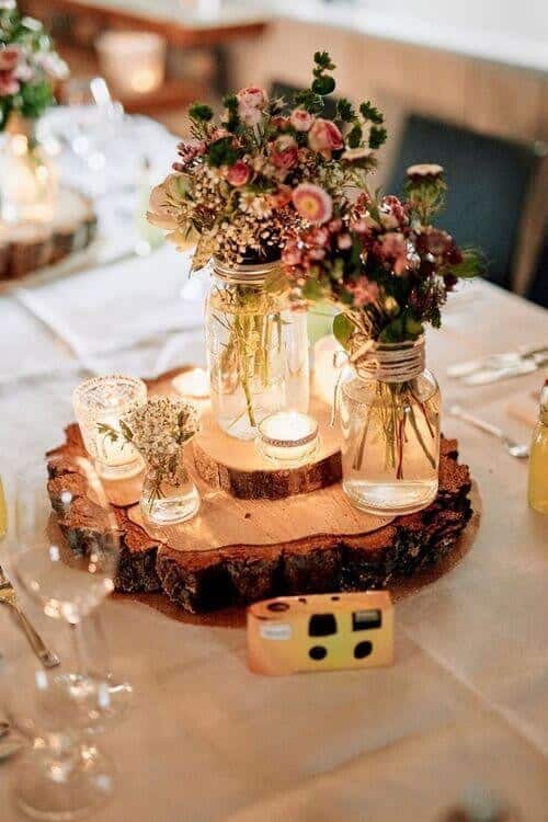 Mason jars filled with flowers and tea lights on wood centerpieces