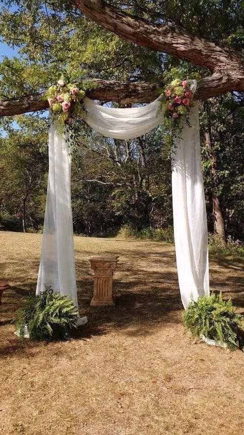 Rustic wedding arch made with fabric and flowers