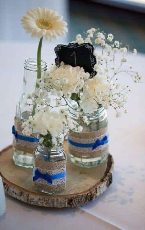 Mason jars with white flowers wrapped in blue ribbon and lace